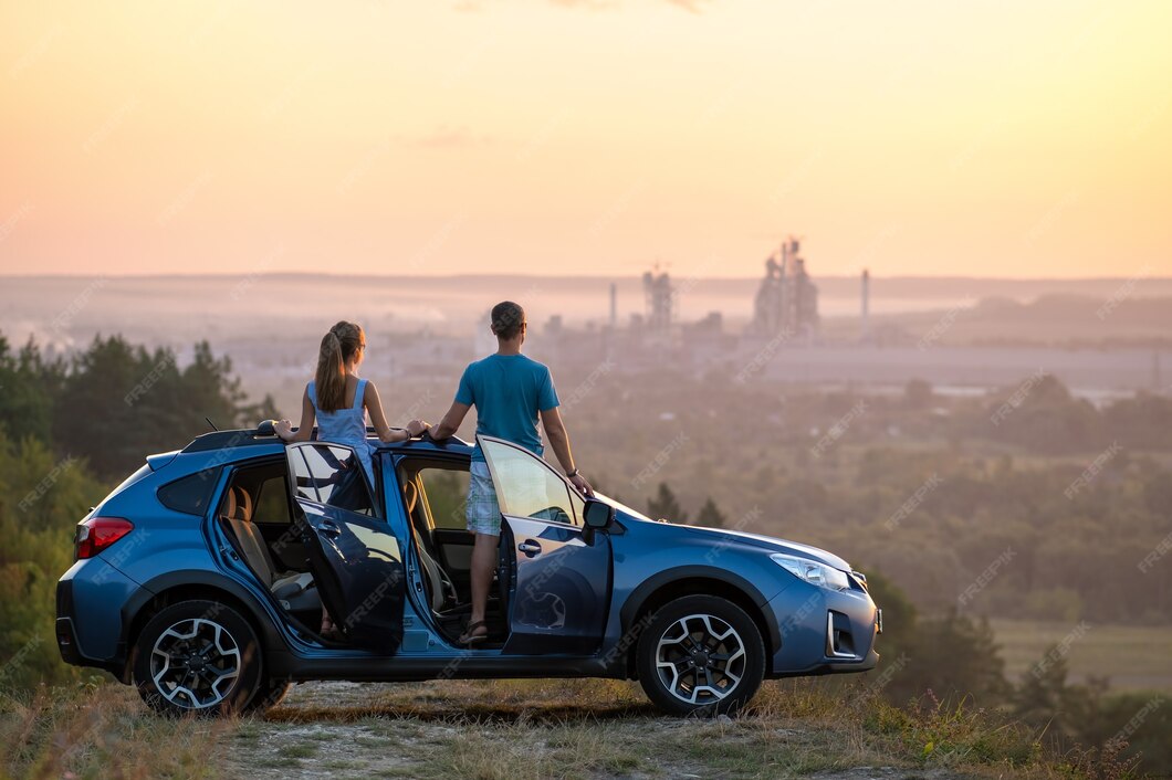 Couple standing beside a car at sunset